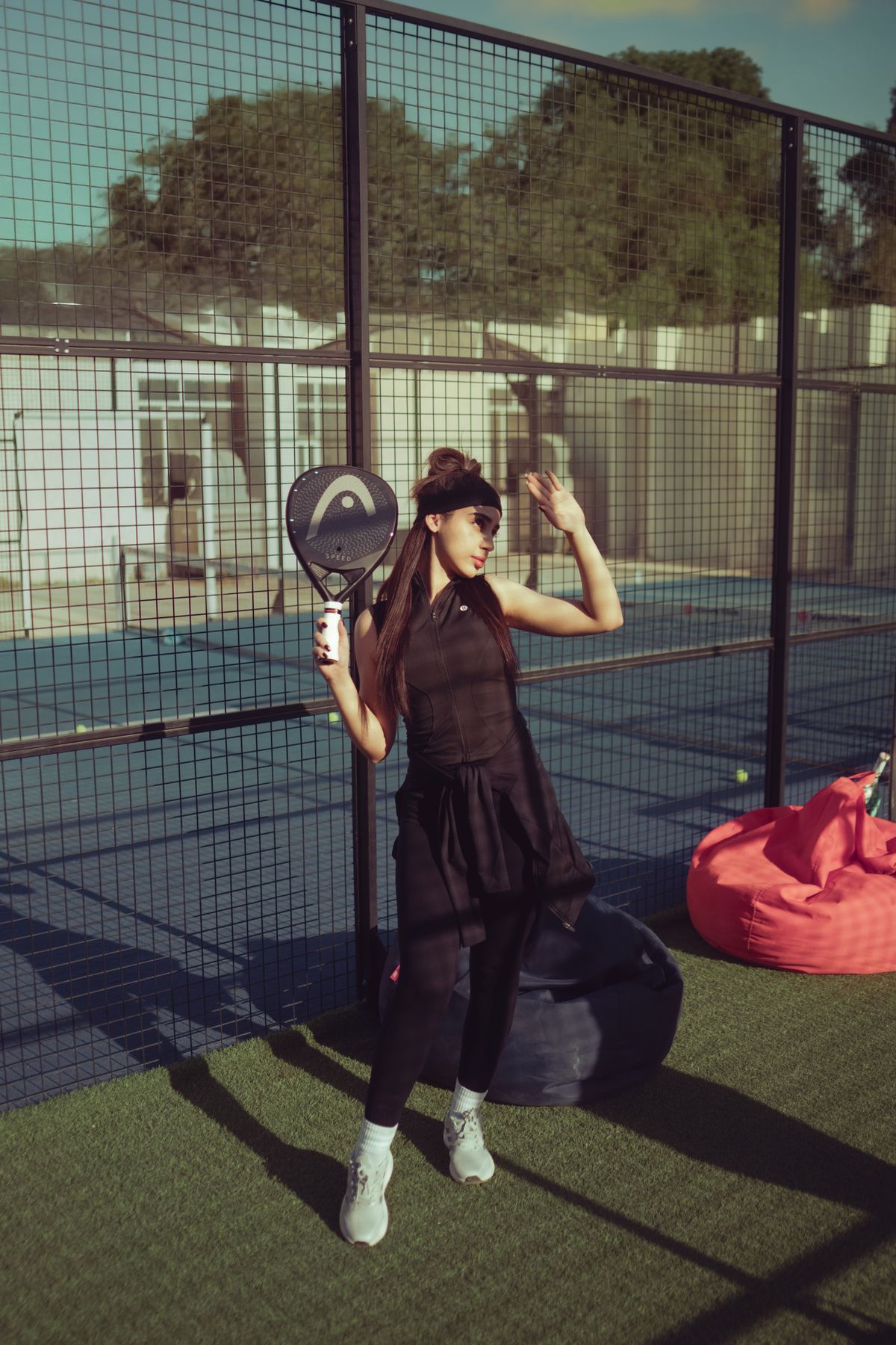 Speelster in legging met HEAD padelracket in de padelkooi
