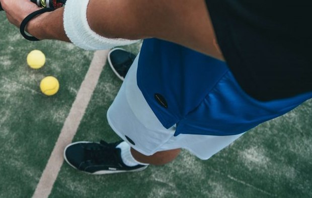 Padelschoenen en ballen op de baan bij de servicelijn