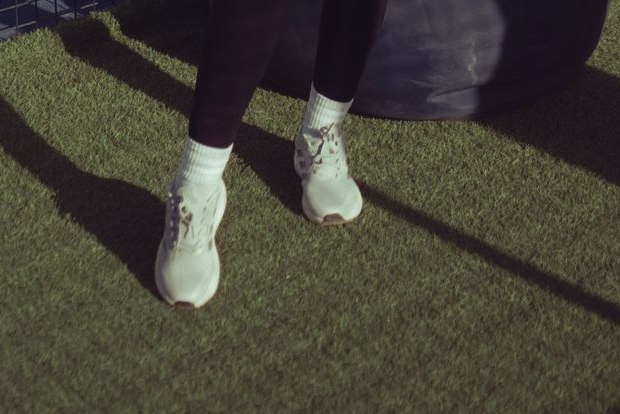 Witte padelschoenen met sokken op kunstgras van de baan