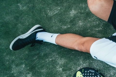 Witte padelsok in zwarte schoen op de baan